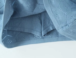 Detailed macro view of the hollow geometric knit pattern and lining of the blue skirt