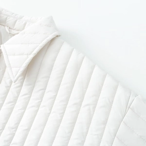 Detail view of white quilted jacket showing fine vertical stitching and neckline texture