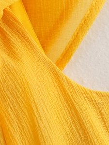 Macro du tissu crêpe jaune vif avec de fines textures froissées et des coutures soignées