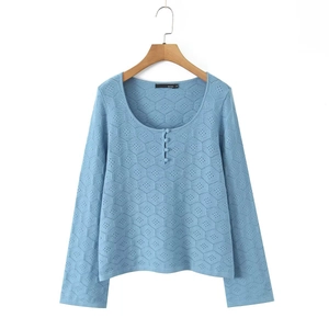 Detail view of light blue knit top with hexagonal honeycomb texture and three buttons