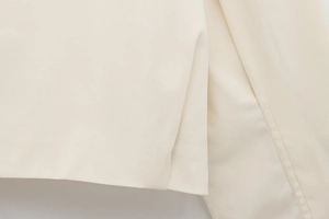 Detailed macro view showing twill fabric texture and side vent slit of the beige jacket