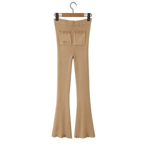 Dettaglio dei pantaloni svasati in maglia kaki con ricamo Lucky e bordi a onde