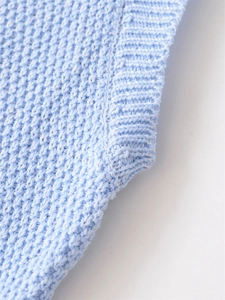 Detailed close-up of light blue knit vest showing premium ribbed texture and soft edge finish