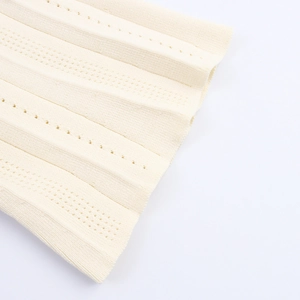 Gros plan sur un tissu en maille beige avec plis verticaux et détails en pointelle