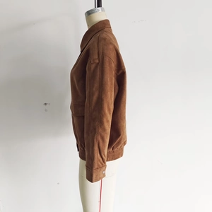 Detail showing brown suede texture, lapel collar, and shoulder epaulets on a bomber jacket