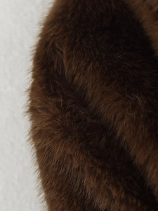 Nahaufnahme der dunkelbraunen Kunstpelz-Textur an einem langärmeligen Wintermantel