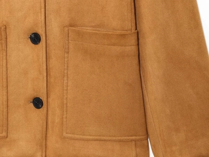 Détail d'une veste en suédine marron avec de grandes poches plaquées et des boutons noirs