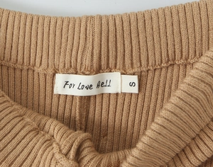 Dettaglio in maglia a coste kaki con etichetta For Love Bell e indicazione taglia S