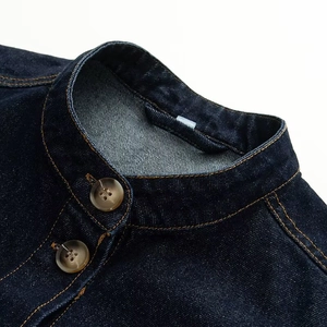 Detailopname van de opstaande kraag met amberen knopen op een denim jack