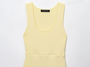 Dettaglio dello scollo a U e della cucitura in vita sul top in maglia giallo chiaro