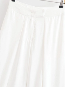 Gros plan détaillé du pantalon large blanc montrant la texture du tissu et les coutures