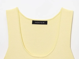 Dettaglio dello scollo dell'abito in maglia giallo chiaro con trama fine ed etichetta