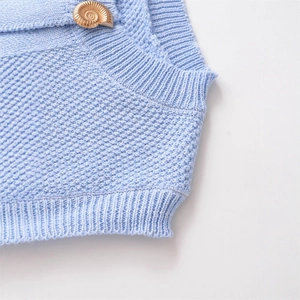 Light blue knit vest with unique gold snail-shaped button detail and textured weave