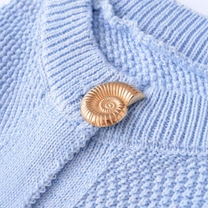 Women's light blue knit vest featuring a decorative gold shell button and fine texture