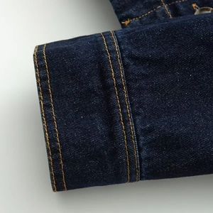 Detail van de manchet van de donkerblauwe denim jas met geel contrast dubbel stiksel