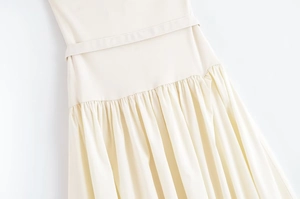 Close-up of cream strapless dress waist detail featuring a matching belt and pleated skirt