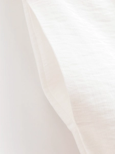 Vue macro d'un pantalon en lin blanc montrant les poches latérales et la texture