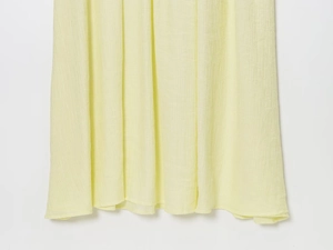 Dettaglio ravvicinato del tessuto a maglia plissettato giallo chiaro con texture a pieghe