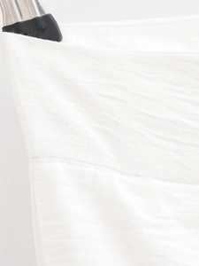 Gros plan sur la texture du tissu blanc du pantalon large et détails de couture