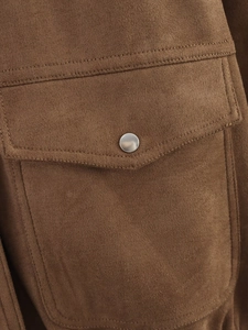Detail of a brown suede jacket pocket featuring a metallic button and clean stitching