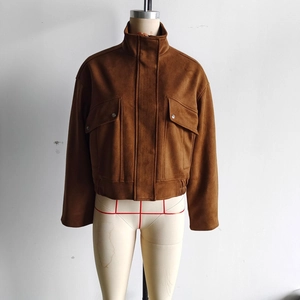 Détail d'une veste en daim beige avec col montant et grandes poches à rabat et boutons pressions