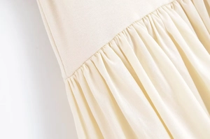 Close-up of cream pleated dress waist with delicate stitching and fabric texture