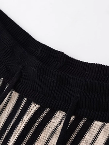 Detail of high-waist elastic waistband on black and beige striped knit trousers