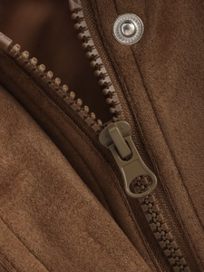 Macro detail of brown suede jacket showing plastic zipper and silver metal snap button
