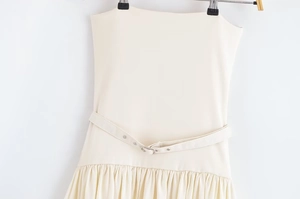 Detailed view of cream-white strapless dress with waist belt and ruffled pleated skirt
