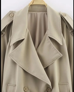 Detail of khaki trench coat featuring wide lapels, epaulets, and premium twill fabric