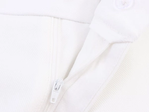Detail of white linen blend trousers showing zipper closure and neat stitching