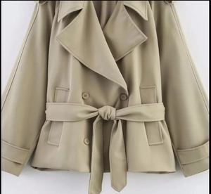 Detail of khaki cropped trench coat featuring lapel collar, double-breasted buttons and belt
