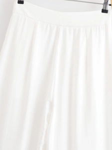 Gros plan du pantalon blanc taille haute à jambes larges montrant plis et texture du tissu