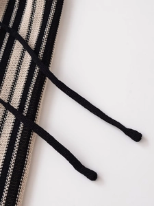 Macro detail of black and white striped knit fabric featuring fine drawstring cords