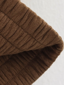 Close-up of deep brown velvet texture with vertical ribbed patterns on fashion jacket