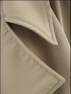 Close-up of khaki trench coat showing premium twill cotton fabric and neat stitching
