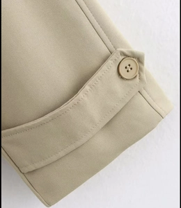 Close-up of khaki trench coat sleeve cuff showing resin buttons and fine stitching