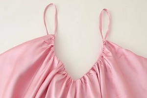Close-up of pink satin dress featuring delicate pleated V-neckline and thin straps
