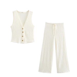 Detail of off-white textured V-neck vest with brown buttons and elastic waist trousers