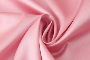 Detail of pink satin fabric with elegant pleated texture and smooth glossy finish