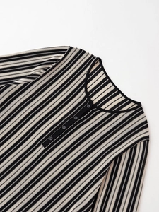 Detailed macro view of the striped knit sweater featuring a classic Henley button neckline