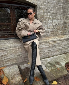Detail shot of khaki trench coat collar and luxury black leather clutch bag with gold logo
