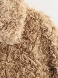 Gros plan macro sur la texture en fausse fourrure camel aux fibres bouclées douces