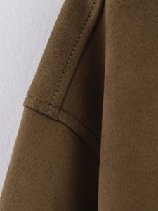 Détail d'une veste en daim marron montrant les coutures et la texture du tissu premium