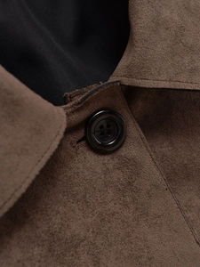 Detail of dark brown faux suede texture with high-shine black button and smooth inner lining