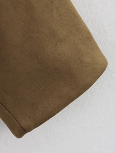 Détail macro de la texture du daim camel et des coutures professionnelles sur la veste