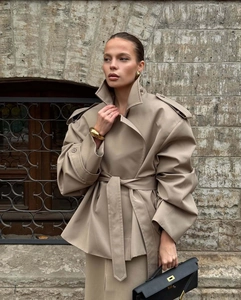 Detail of khaki short trench coat featuring lapel collar, epaulettes, and sleeve pleats