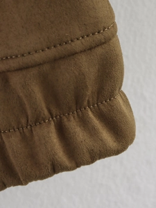 Détail de la veste en daim marron montrant le poignet élastique et la double couture