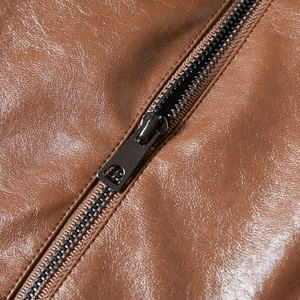 Macro detail of brown PU leather jacket featuring lychee texture and diagonal metal zipper