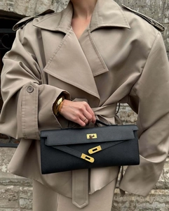 Close-up of black textured leather clutch featuring a classic gold-tone metal twist lock